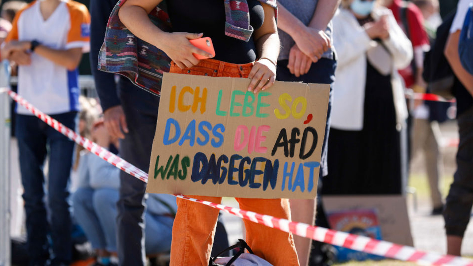 Nahaufnahme auf ein Pappschild mit bunten Wörtern: "Ich liebe so, dass die AfD was dagegen hat"