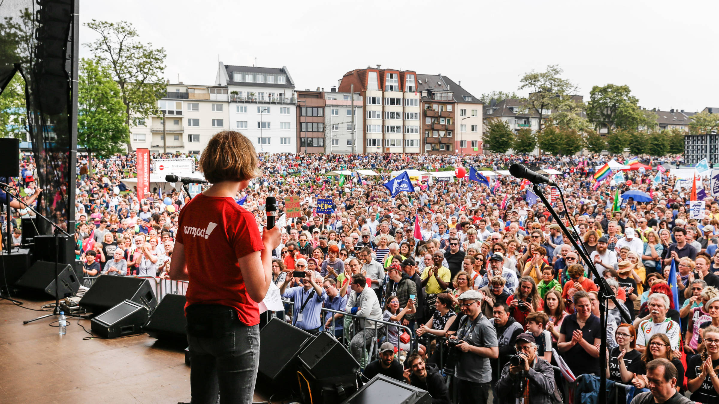 Für ein tolerantes, friedliches und zukunftsfähiges Europa gingen 2019 viele Menschen bei Europa-Demos auf die Straße, wie hier in Köln. Eine Person mit Campact-Shirt steht auf einer Demobühne und hält eine Rede.