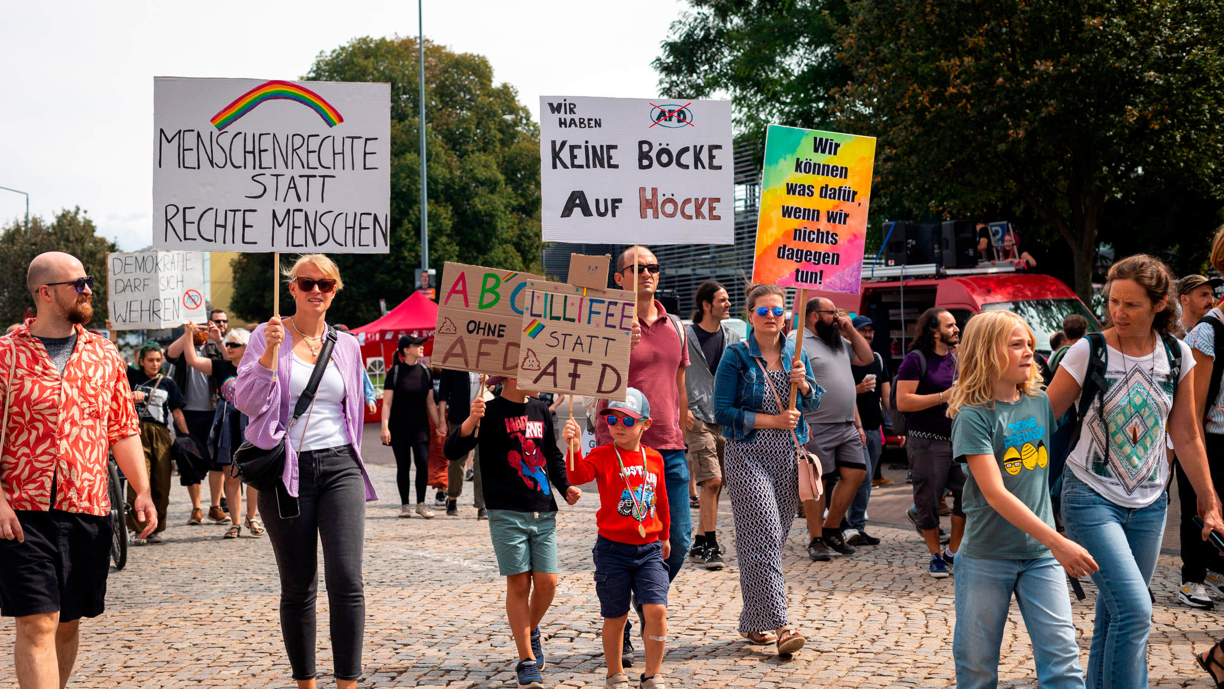 Erwachsene und Kinder demonstrieren in Erfurt mit bunten Schildern gegen die AfD und für die Demokratie.